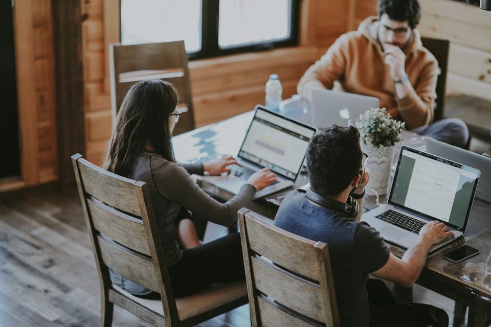 Equipe trabalhando em notebooks em uma mesa de madeira